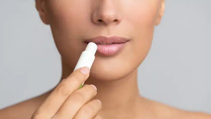 woman applying chapstick as budget lip primer