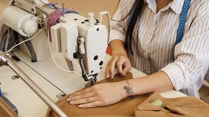 Woman sewing a ilttle brown dress.