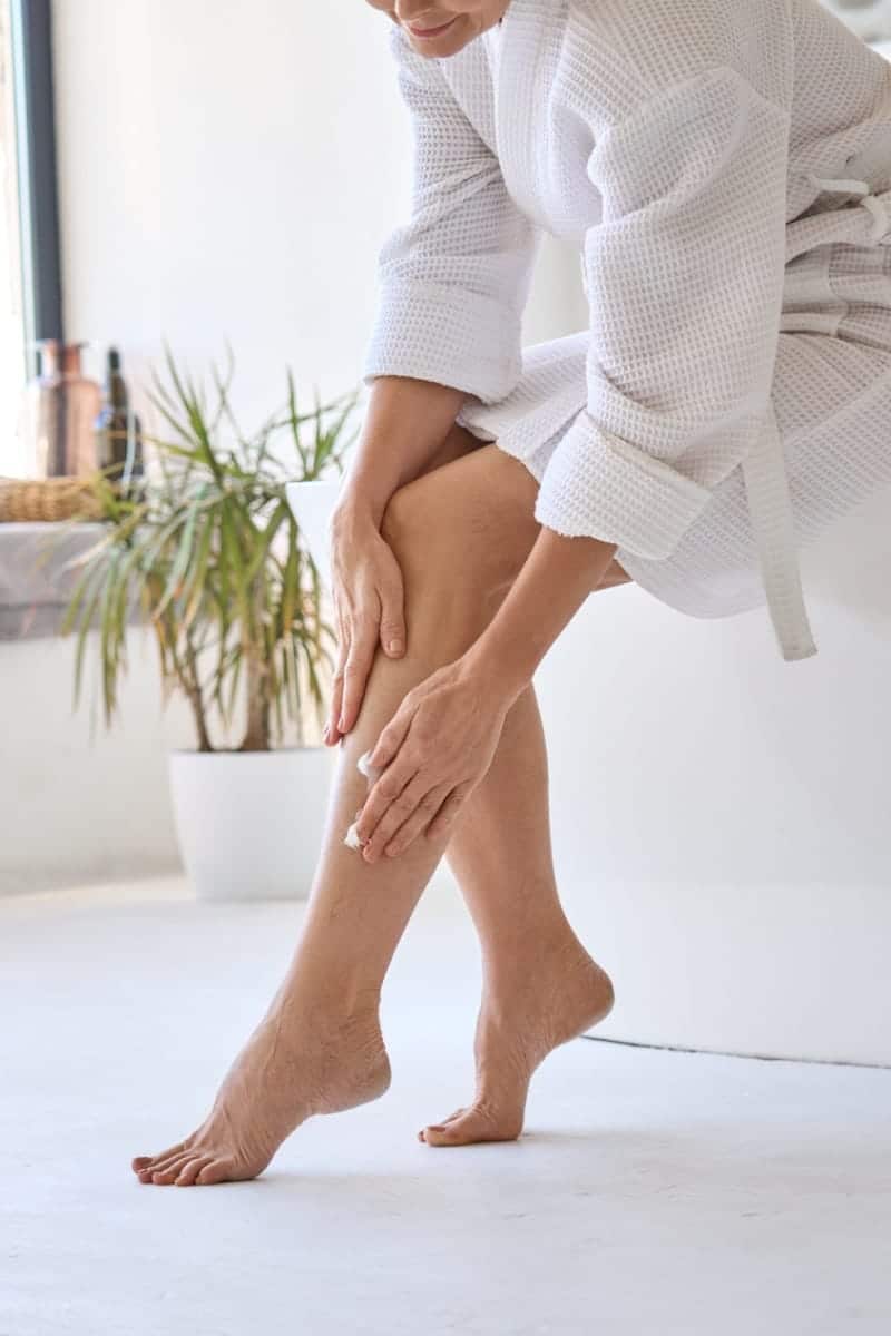 View of woman's lower legs as she applies lotion.