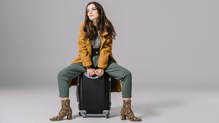 Woman sitting on top of luggage
