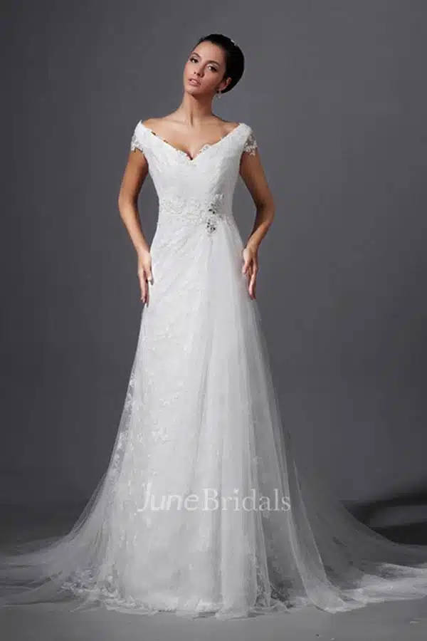 Model wears long tulle white wedding dress with train.