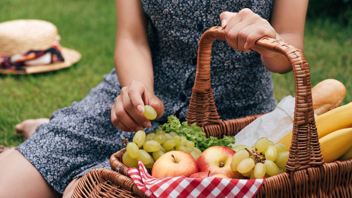 Woman in picnic outfit near basket of food
