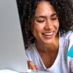 Smiling woman shopping online to represent why shop Amazon.