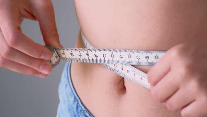 Person measures waistline to represent dressing for your body type.