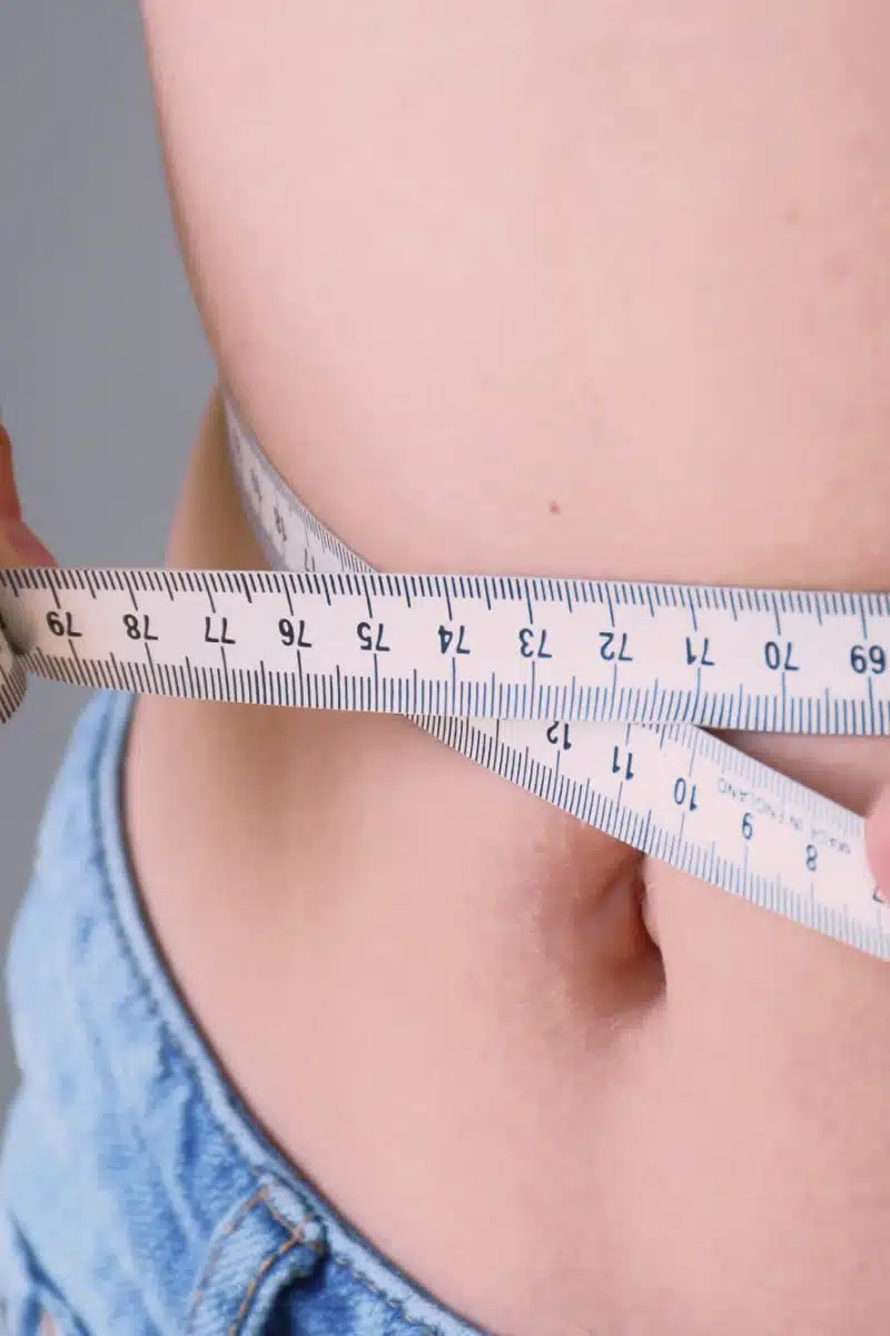 Person measures waistline to represent dressing for your body type. 