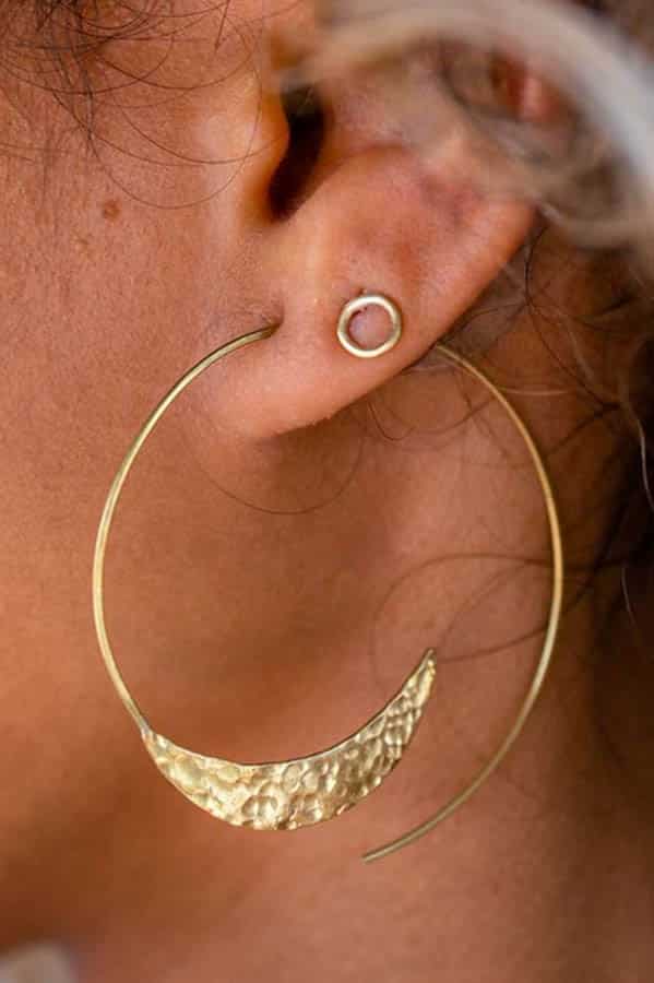 Close up of woman's ear, adorned with a curved hoop earring from Purpose Jewelry.