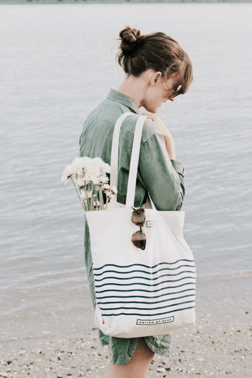 Girl on beach holding striped canvas tote