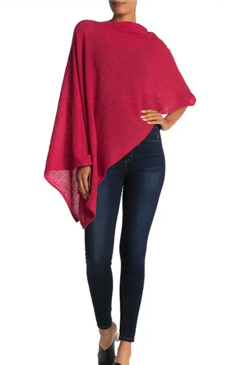 Woman wears red cape over skinny jeans.