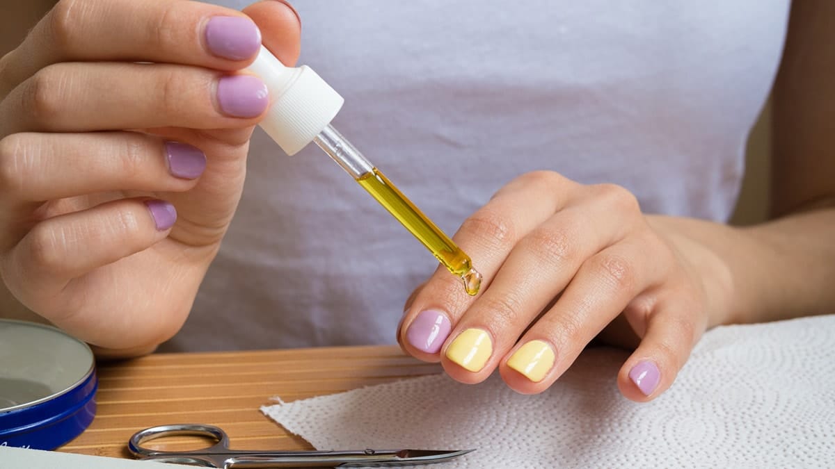 Woman practicing cuticle care by applying cuticle oil