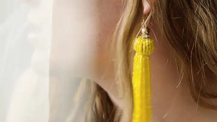 Close-up of woman wearing trendy summer jewelry -- long yellow earrings.