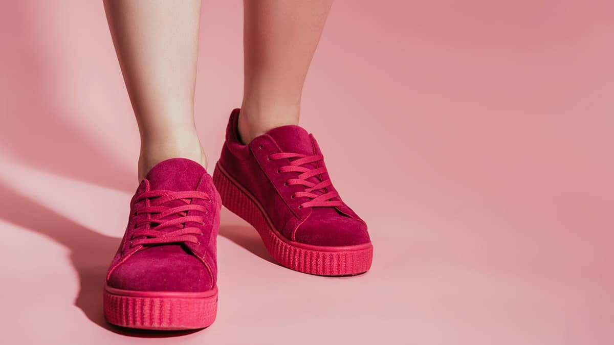 Close up of women's legs with bright pink platform sneakers