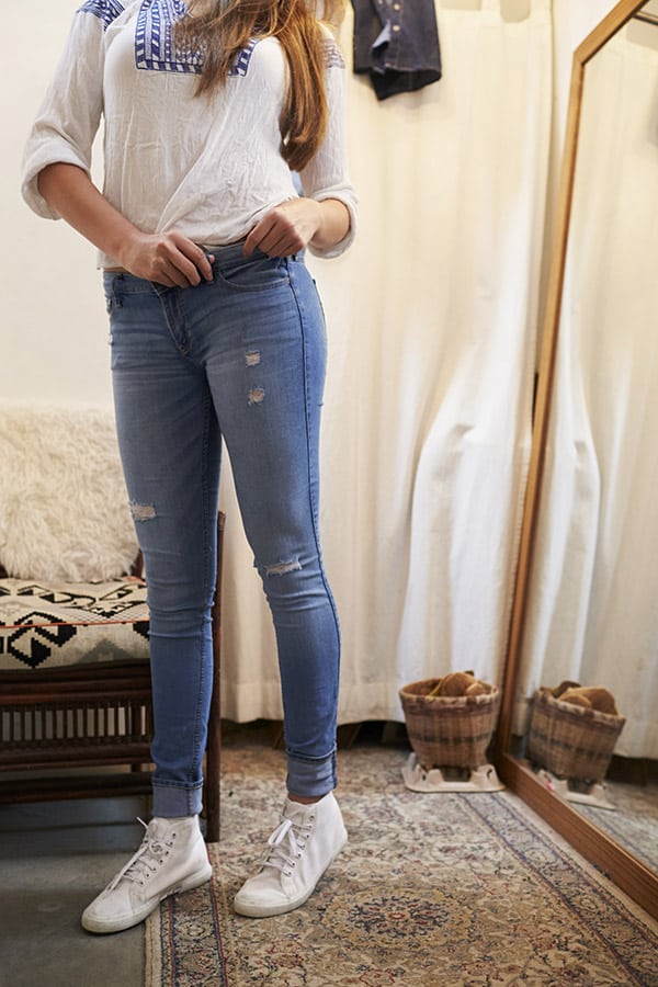 Woman trying on jeans and looking in the mirror.