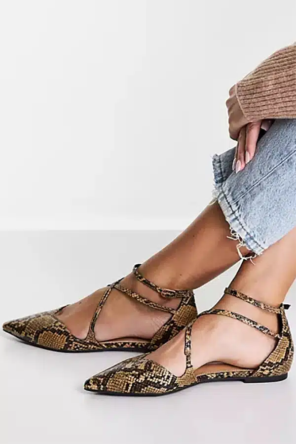 Close-up of women's lower legs wearing snake print flat sandals.