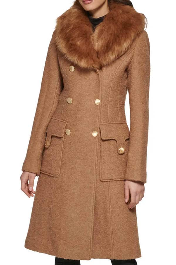 Model wears camel coat with fur trim.