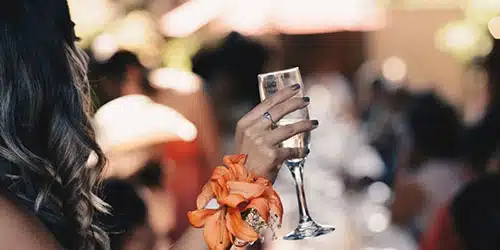 Close-up of female hand holding champagne glass at wedding.