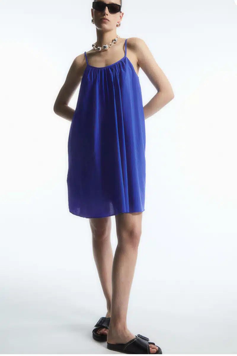 Model wears blue mini dress from COS midrange fashion store.