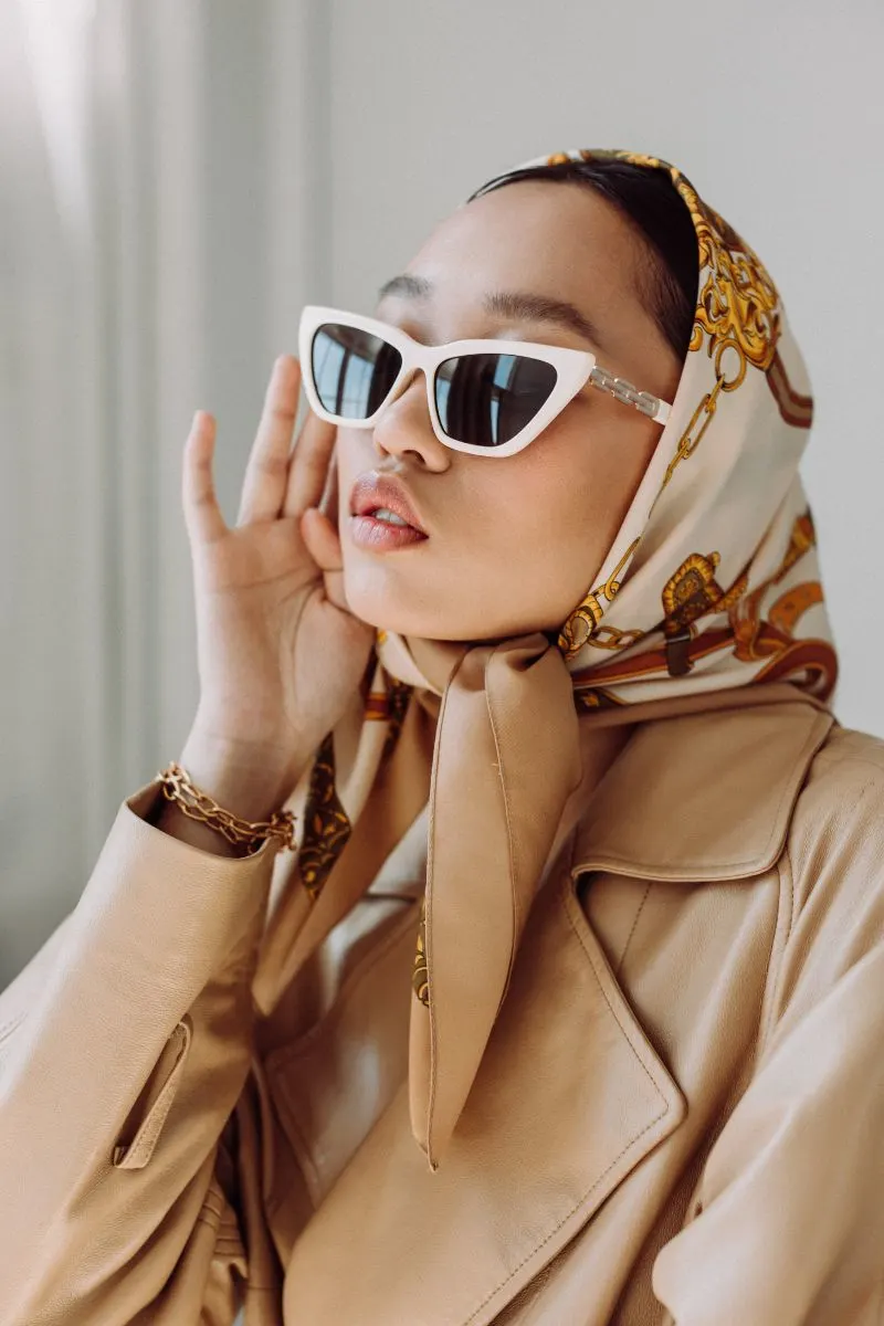 Woman wearing silk scarf as headwrap and sunglasses.