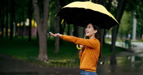 Woman standing out in rain with umbrella.